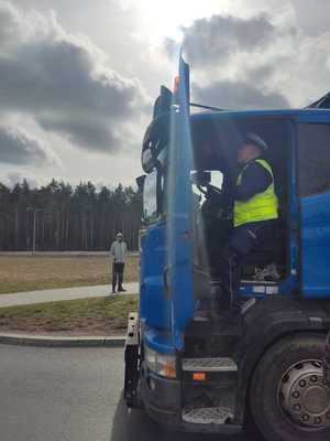 Policjant wsiadający do kabiny ciężarówki.