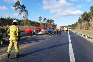 widok na całe miejsce wypadku drogowego na którym widać rozbite samochody i służby ratunkowe