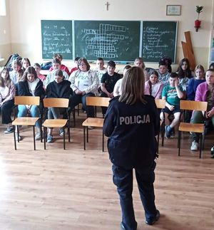 Policjantka stoi na przeciwko uczniów siedzących na krzesłach