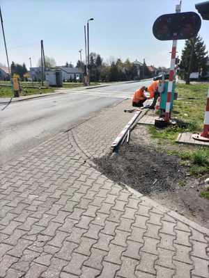 Widok na osoby naprawiające szlaban przy przejeździe kolejowym