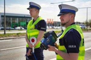 Dwóch policjantów stoi przy drodze i obserwuje ruch drogowy
