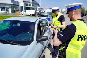 dwóch policjantów kontroluje zatrzymany samochód