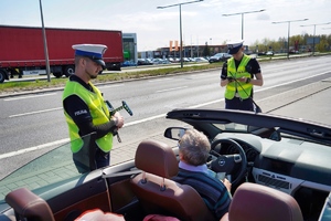 Dwóch policjantów kontroluje zatrzymany samochód