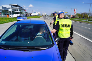 Dwóch policjantów kontroluje zatrzymany samochód
