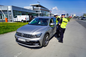 Dwóch policjantów kontroluje zatrzymany samochód