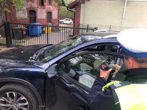 Policjant mierzy przejrzystość przedniej bocznej szyby w samochodzie