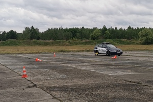 Policjant kieruje radiowozem z zamontowanym trolejem przez tor przeszkód.