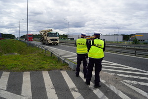 Policjanci podczas pomiaru prędkości. W tle nadjeżdżające samochody.