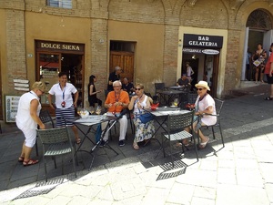Turyści siedzący przy stolikach przed kawiarnią..