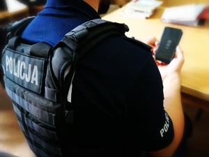 Policjant trzyma telefon.