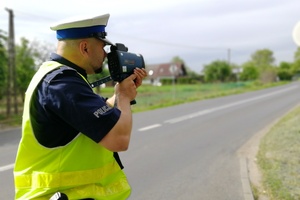 Policjant z miernikiem prędkości podczas pomiaru.