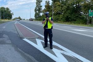 policjant mierzy na drodze ręcznym miernikiem prędkości