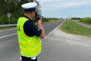 policjant mierzy na drodze ręcznym miernikiem prędkości