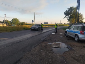 Jeden policjant kontroluje kierowcę skody, a drugi stoi na poboczu