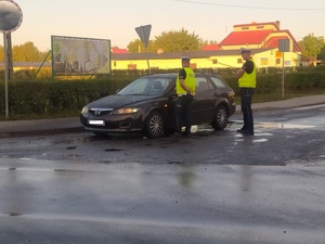 Jeden policjant kontroluje trzeźwość kierowcy mazdy, a drugi stoi obok