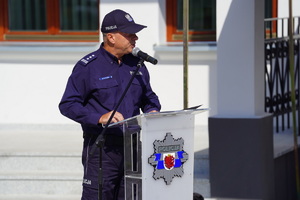 policjant przemawia do mikrofonu do zgromadzonych gości i funkcjonariuszy