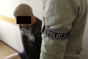 Złodziej siedzi, a obok stoi policjant