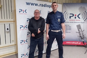 Policjant wraz z dziennikarzem stoją na tle baneru radia