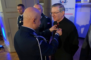 policjant przypina księdzu medal