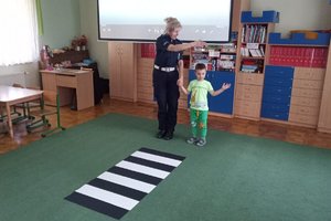Policjantka instruuje przedszkolaka, jak przechodzić po pasach