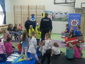 Policjanci z dziećmi na sali gimnastycznej w trakcie zajęć.