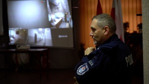 Policjant stoi na przeciwko ekranu z monitorami