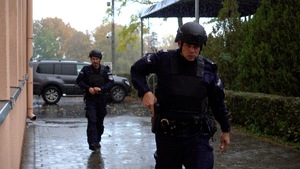 dwóch policjantów wyciąga broń z kabur i idą chodnikiem