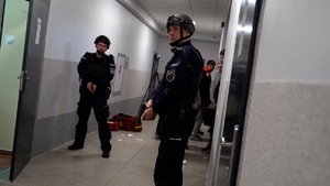 policjanci zabezpieczają na korytarzu ewakuację dzieci