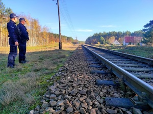 Policjanci stoją przy torach i patrzą na nie