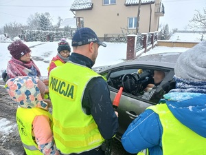 Policjant i dzieci przy samochodzie.