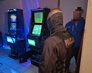 Policjant i zatrzymany mężczyzna w pomieszczeniu z automatami do gier.