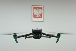 dron w powietrzu w pomieszczeniu. w tle godło Polski