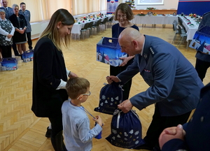 policjant przekazuje prezenty dwójce dzieci