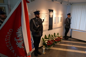 ujęcie na Tablicę Pamięci, przy których stoją dwaj policjanci z karabinkami, ubrani w umundurowanie galowe