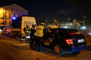 policjanci kontrolują kierowcę taksówki, obok stoi radiowóz Inspekcji Transportu Drogowego