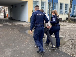 Policjanci prowadzą zatrzymanego oszusta