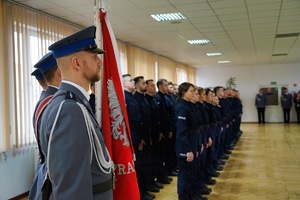 Poczet sztandarowy na tle policjantów biorących udział w ślubowaniu