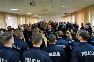 Komendant przemawia do nowo przyjętych policjantów którzy stoją obok niego