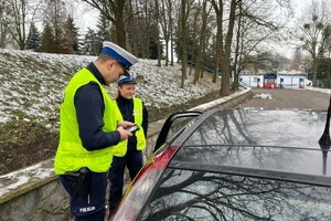 Policjanci kontrolują zatrzymany samochód