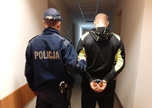 Policjant prowadzi drugiego ze sprawców