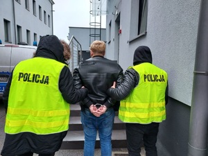 dwaj policjanci prowadzą zatrzymanego skutego kajdankami