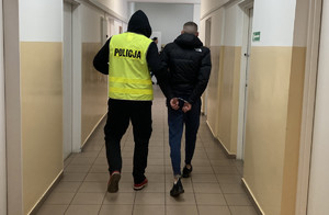 policjant prowadzi zatrzymanego skutego kajdankami