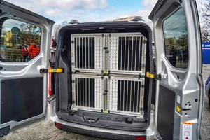 Wnętrze samochodu do przewozu psów służbowych. Tył furgonu, widać cztery kojce dla psów.