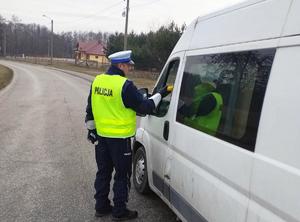 Policjant stoi przy samochodzie zatrzymanym do kontroli i sprawdza trzeźwość kierowcy