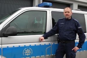 umundurowany policjant stoi przy radiowozie