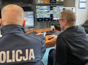 Policjant i mężczyzna siedzą na przeciwko monitorów