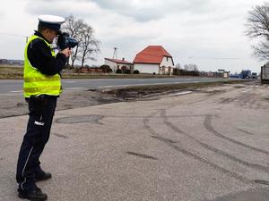 Policjant stoi przy drodze i kontroluje prędkość