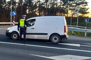 Policjant kontroluje zatrzymany samochód i sprawdza trzeźwość kierowcy