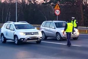 Policjant kontroluje zatrzymany samochód i sprawdza trzeźwość kierowcy