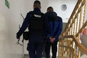 Policjant prowadzi zatrzymanego mężczyznę